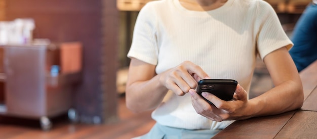 Mujer de negocios casual sosteniendo y usando un teléfono inteligente para mensajes sms mujer joven escribiendo un teléfono móvil con pantalla táctil en un café o tecnología de estilo de vida de oficina moderna Redes sociales y concepto de red