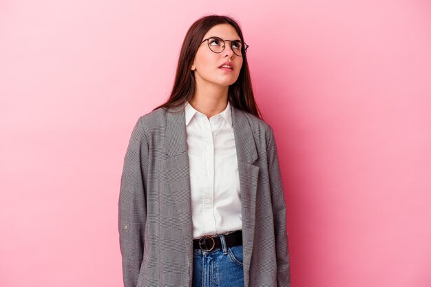 Mujer de negocios caucásica joven aislada en la pared rosada cansada de una tarea repetitiva.