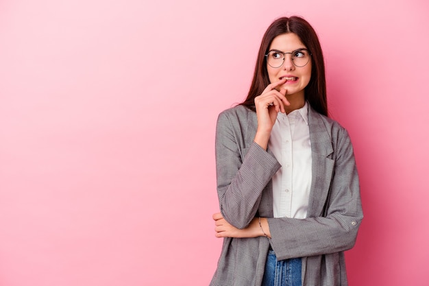 Mujer de negocios caucásica joven en rosa relajado pensando en algo mirando un espacio de copia.