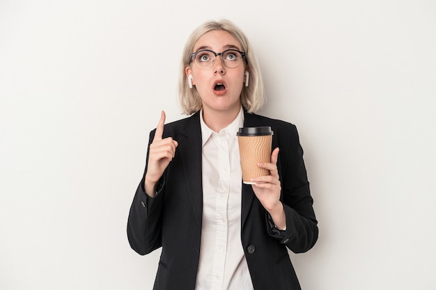 Mujer de negocios caucásica joven sosteniendo café para llevar aislado sobre fondo blanco apuntando al revés con la boca abierta.