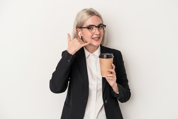 Mujer de negocios caucásica joven sosteniendo café para llevar aislado sobre fondo blanco mostrando un gesto de llamada de teléfono móvil con los dedos.