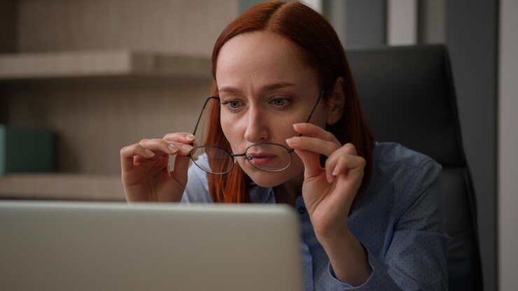Foto mujer de negocios caucásica en oficina trabajo con computadora mujer de negocios niña trabajadora mujer sentada en el escritorio trabajo en portátil quitarse las gafas comprobar lentes ópticas problema mala visión visión borrosa gafas
