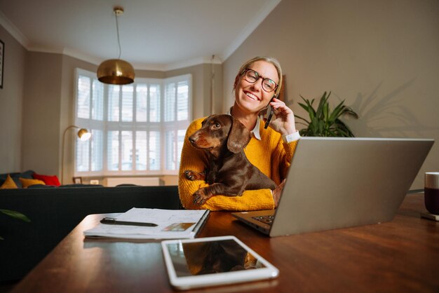 Mujer de negocios caucásica que trabaja en casa con un perro mascota