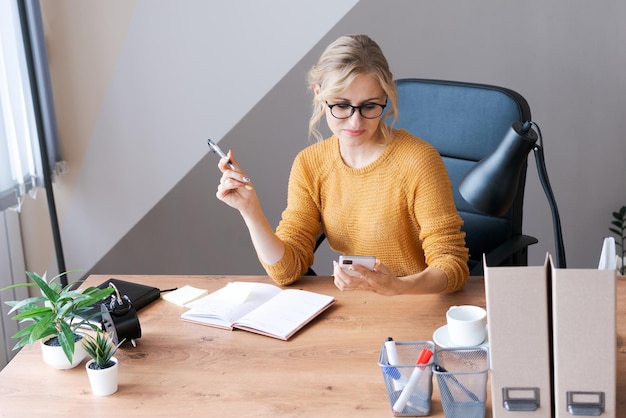 La mujer de negocios caucásica se sienta en la oficina en la mesa y escribe candados