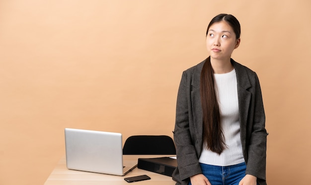 Mujer de negocios china en su lugar de trabajo y mirando hacia arriba