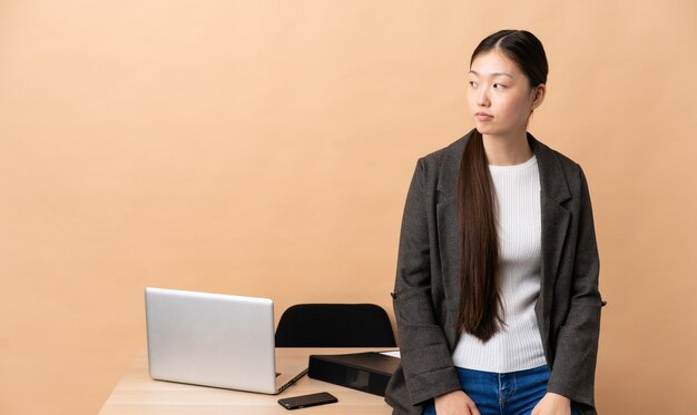 Mujer de negocios china en su lugar de trabajo mirando hacia el lado