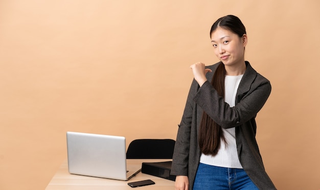 Mujer de negocios china en su lugar de trabajo orgullosa y satisfecha de sí misma