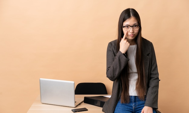 Mujer de negocios chinos en su lugar de trabajo mostrando algo