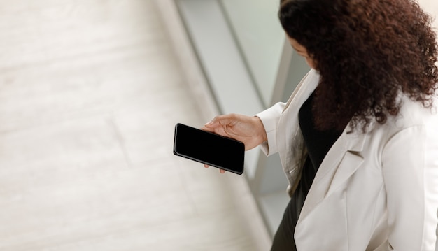 Foto mujer de negocios clotes sosteniendo y mirando la pantalla en blanco del teléfono inteligente en la mano.