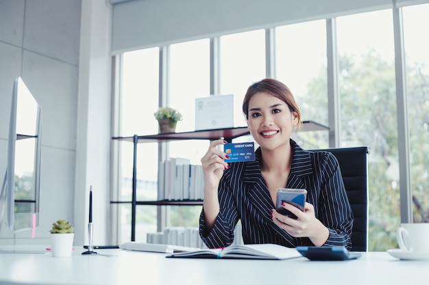 Mujer de negocios de compras en línea a través de teléfono móvil con tarjetas de crédito, pagar facturas.