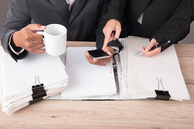 Mujer de negocios comprobar el teléfono en el escritorio de trabajo.