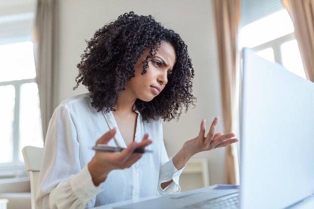 Mujer de negocios confundida molesta por problemas en línea correo electrónico no deseado o noticias falsas de Internet mirando a una trabajadora de oficina portátil que se siente sorprendida por la computadora atascada desconcertada por un mensaje de estafa o virus