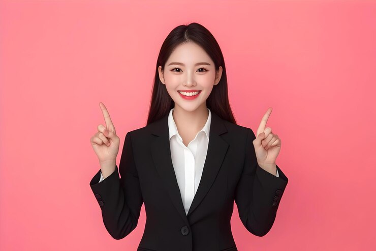Una mujer de negocios coreana sonriente apuntando con los dedos hacia arriba mostrando una pancarta publicitaria o un logotipo en la parte superior