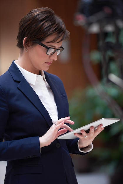 mujer de negocios corporativa que trabaja en una tableta en el interior de la oficina moderna