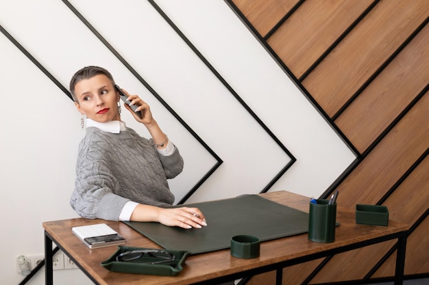 Mujer de negocios con corte de pelo corto hablando por teléfono en la oficina