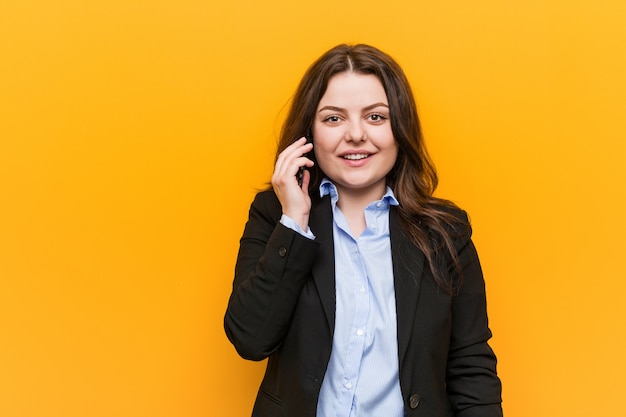 Mujer de negocios con curvas más tamaño joven sosteniendo un teléfono feliz, sonriente y alegre.