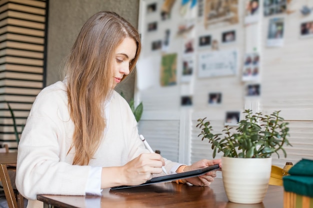 Mujer de negocios con un dispositivo portátil que trabaja en una oficina abierta