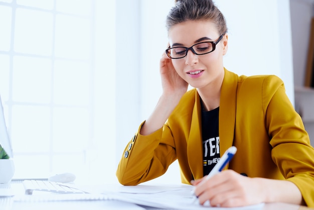 Mujer de negocios con el documento de lectura de escritorio en su oficina