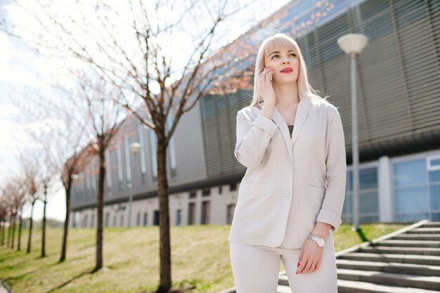 Mujer de negocios elegante en gafas de sol con teléfono. Mujer de negocios con teléfono cerca de la oficina.