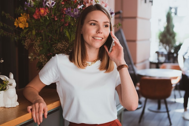 Mujer de negocios elegante hablando por teléfono inteligente en la tienda de flores