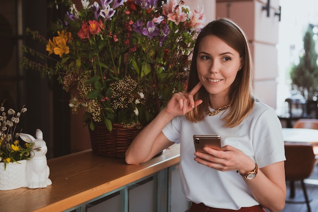 Mujer de negocios elegante con smartphone en floristería