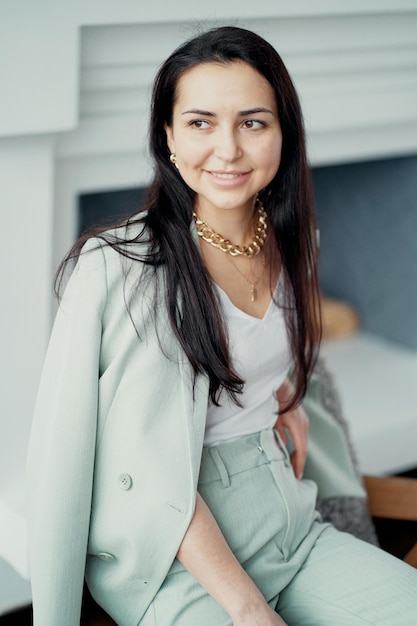 Una mujer de negocios con un elegante traje verde trabaja en una nueva oficina elegante y está esperando socios