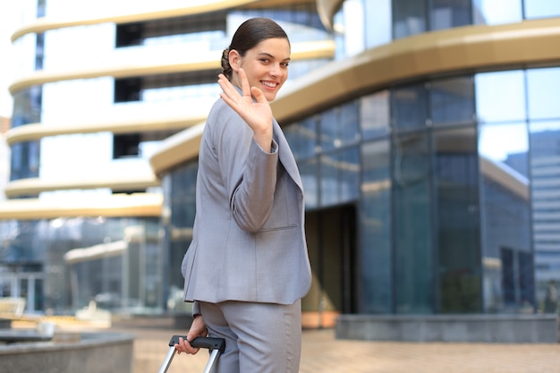 Mujer de negocios elegante viajando con estuche en el aeropuerto. Hermoso viaje femenino con estilo con equipaje.