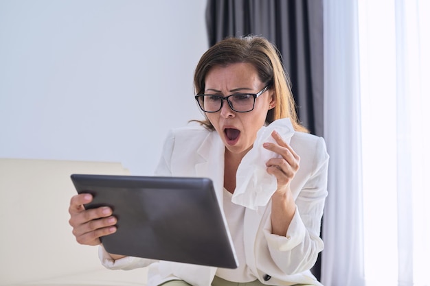 Mujer de negocios enferma estornudando en pañuelo haciendo videollamadas, mujer mirando webcam de tableta digital hablando con un médico. Mujer haciendo una importante videoconferencia mientras está en casa