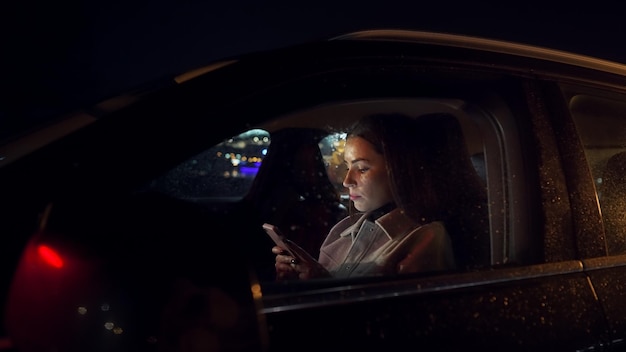 Foto una mujer de negocios enfocada que desplaza el teléfono móvil en el conductor se sienta mientras viaja desde la oficina en un lugar de lujo