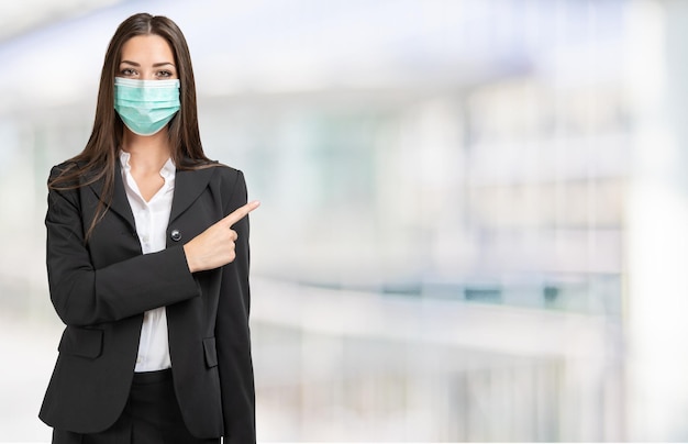 Mujer de negocios enmascarada señalando con el dedo a una habitación brillantemente iluminada