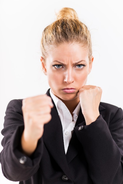 Mujer de negocios enojada golpeando boxeo hacia la cámara lista para pelear.