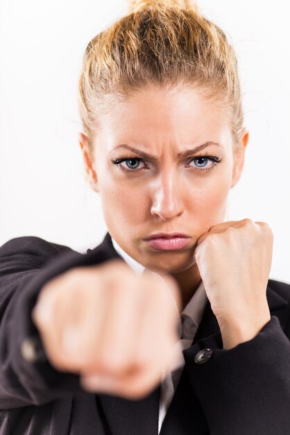 Mujer de negocios enojada golpeando boxeo hacia la cámara lista para pelear.