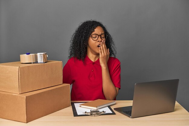 Mujer de negocios de entregas con inventario y cajas bostezando mostrando un gesto cansado