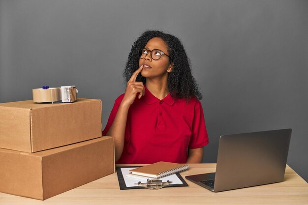 Mujer de negocios de entregas con inventario y cajas mirando hacia los lados con dudas y escepticismo