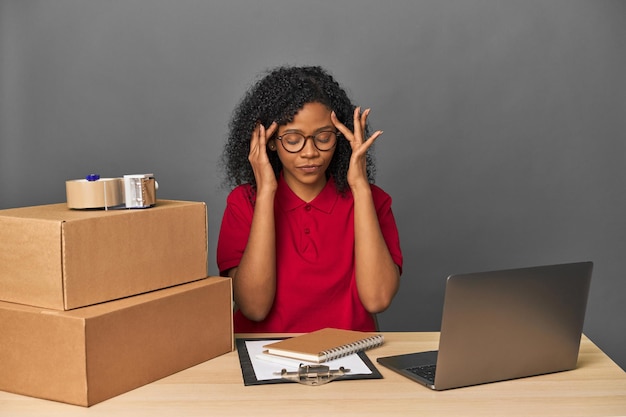 Mujer de negocios de entregas con inventario y cajas tocando las sienes y con dolor de cabeza