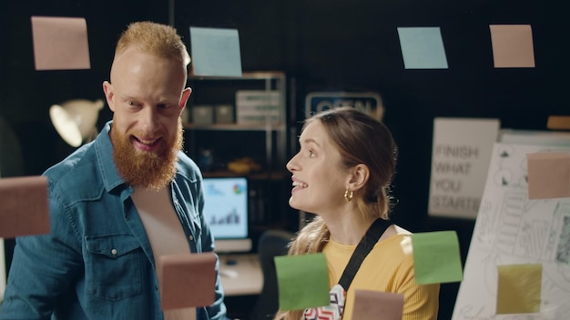 Mujer de negocios entusiasta y hombre profesional sonriendo en la oficina hipster