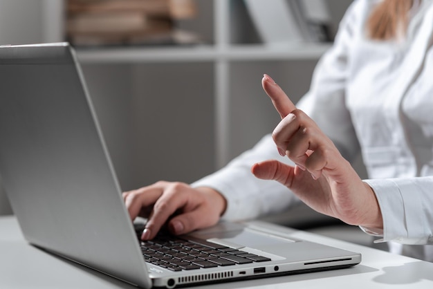 Mujer de negocios escribiendo actualizaciones recientes en el teclado de la computadora portátil en el escritorio y señalando ideas importantes con un dedo mujer en la oficina escribiendo mensajes tardíos en la computadora