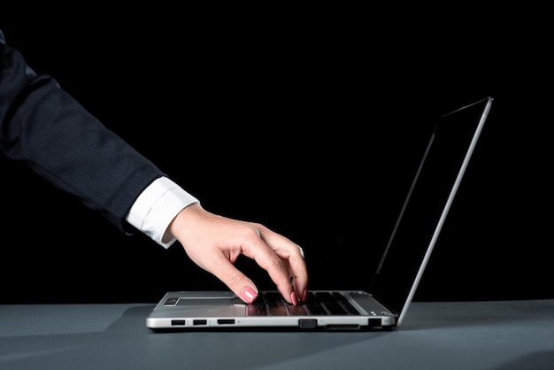 Mujer de negocios escribiendo actualizaciones recientes en el teclado de la computadora portátil en el escritorio