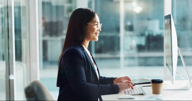 Foto mujer de negocios escribiendo en la computadora y feliz copywriting planificación en línea y software de oficina joven trabajador editor o escritor trabajando en el escritorio para el informe de investigación o la edición del boletín de la compañía