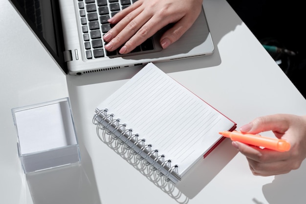 Mujer de negocios escribiendo en cuaderno con marcador en el escritorio con notas y computadora portátil