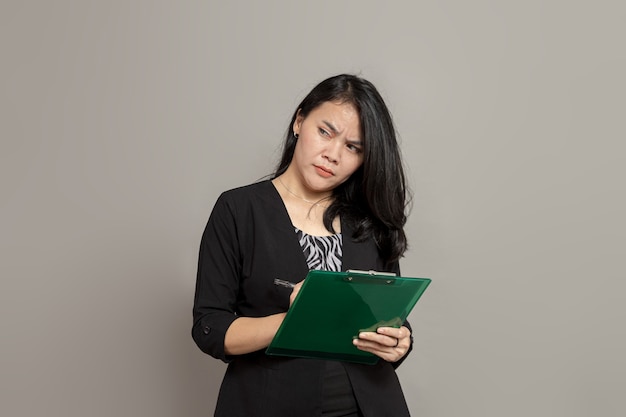 Mujer de negocios escribiendo en el portapapeles con expresión facial confusa