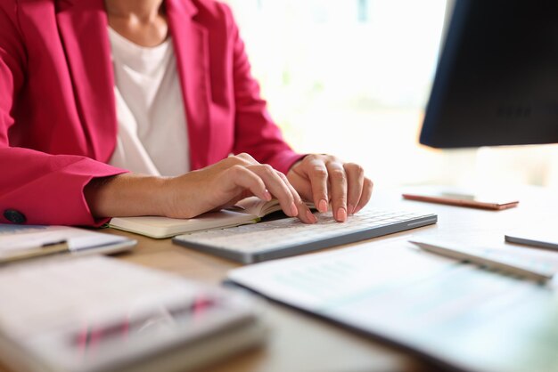 Foto la mujer de negocios está escribiendo en el teclado de la computadora mientras está sentada en su oficina