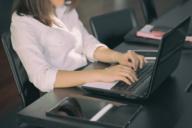 Mujer de negocios escribiendo en el teclado del ordenador portátil