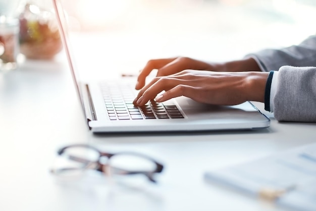 Mujer de negocios escribiendo trabajo en una computadora portátil en su escritorio en una oficina moderna Mujer ocupada haciendo negocios en el teclado trabajando con informes, documentos y correos electrónicos o navegando por Internet en el lugar de trabajo