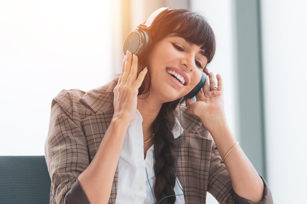 Mujer de negocios escuchando música en la oficina con auriculares