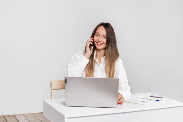 una mujer de negocios está hablando por teléfono con su socio de negocios mientras está sentada en su escritorio