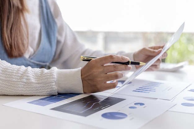 La mujer de negocios está mirando los documentos financieros de la empresa para analizar problemas y encontrar soluciones antes de llevar la información a una reunión con un socio. Concepto financiero.