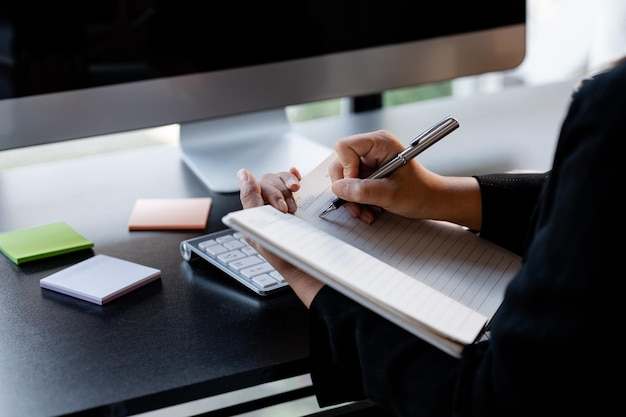 Una mujer de negocios está tomando notas en un cuaderno, revisa los documentos financieros de la empresa y lleva informes correctivos al gerente de finanzas para corregir el concepto de finanzas