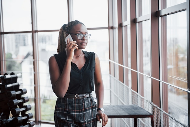 Una mujer de negocios estadounidense habla por su teléfono celular en la oficina.