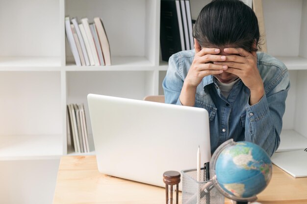 Mujer de negocios estresada con la cabeza en las manos sentada en el escritorio